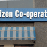 "Citizen Co-operative Bank signboard displaying the bank’s name with a blue and white color scheme, located outside a branch with lockers available for customers."